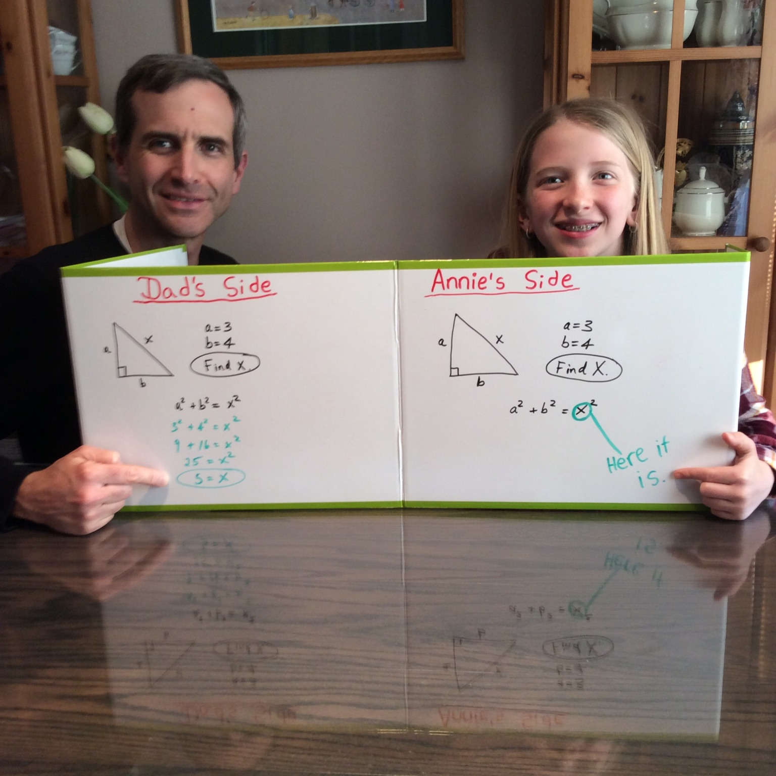 A father and daughter posing with whiteboards with math equations