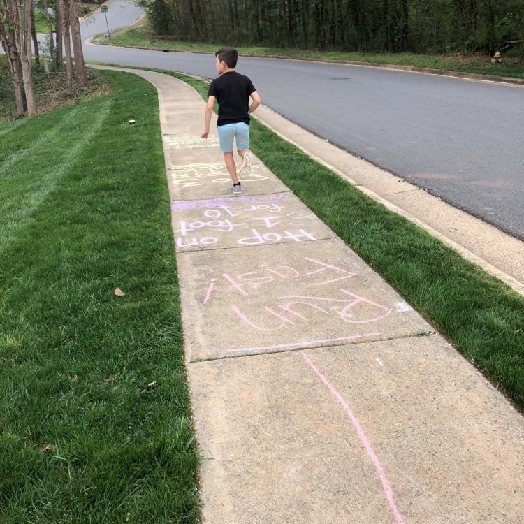 A child running on a sidewalk decorated with chalk drawings