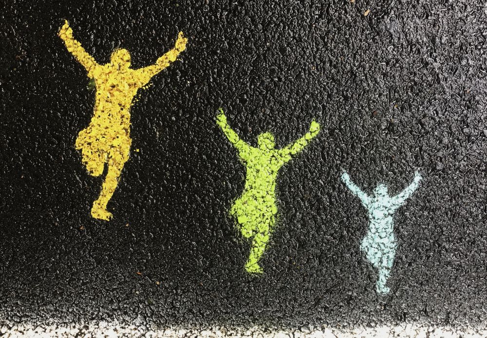 painting on asphalt of 3 people running with their arms outstretched